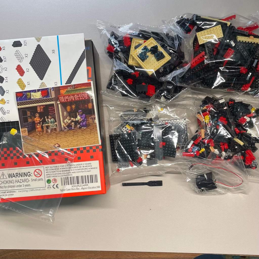 Unboxing the micro block arcade cabinet set reveals four bags containing various bricks, two clear panes, a brick separator, a light piece, a sticker, and a double-sided instruction sheet.